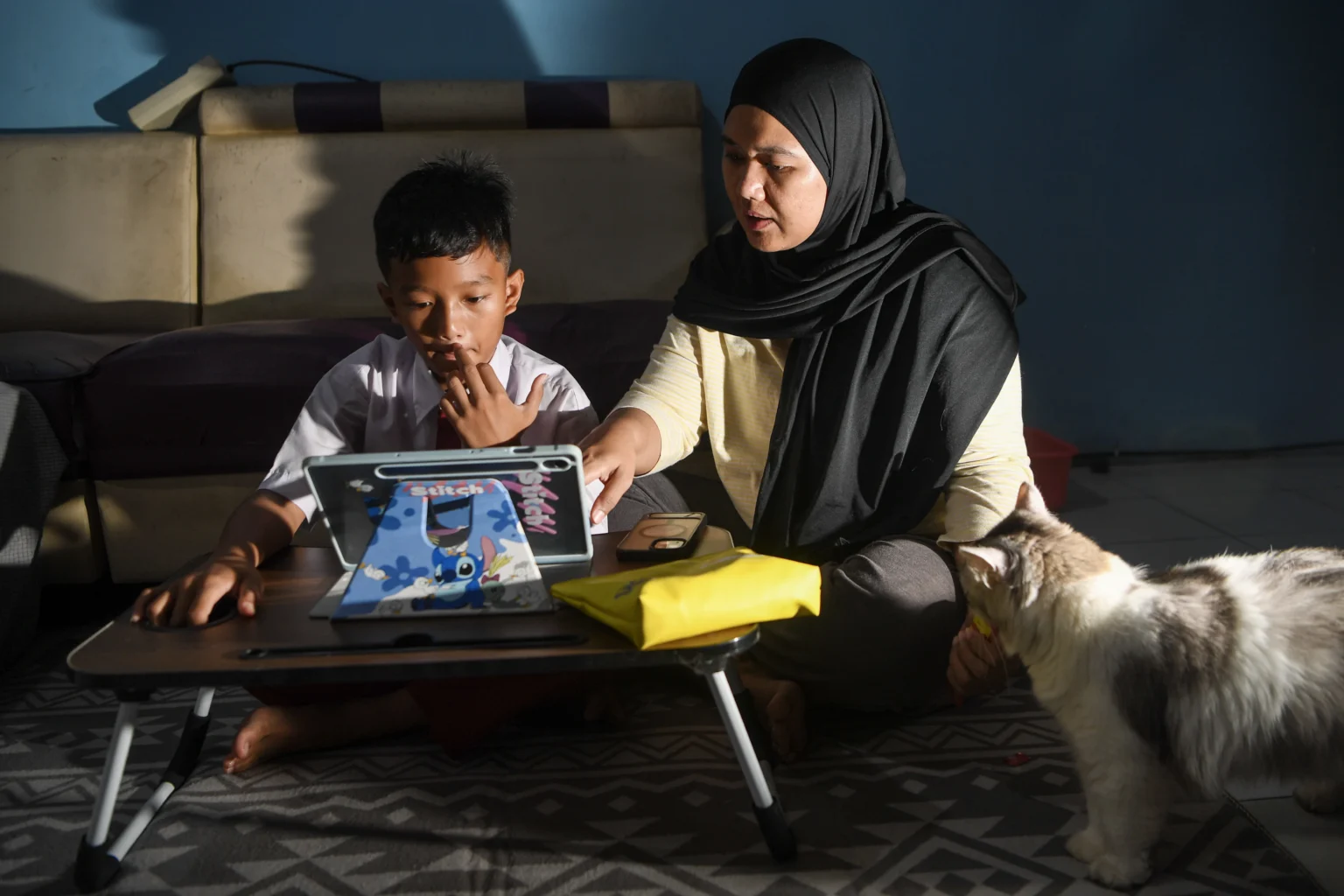 Siswa Sekolah Dasar Negeri 07 Rorotan Pagi, Richie Archilles (kiri), didampingi orang tuanya mengikuti pembelajaran secara daring dari rumah di Jakarta Utara, Senin (7/9/2026).