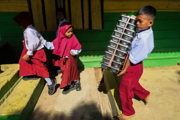 Siswa membawa menu Makan Bergizi Gratis (MBG) menuju ke dalam kelas di SDN 13 Konda, Kabupaten Konawe Selatan, Sulawesi Tenggara, Senin (24/8/2026).